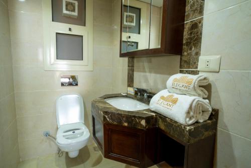 a bathroom with a sink and a toilet and towels at LOFTS by Elegant Hospitality in Cairo