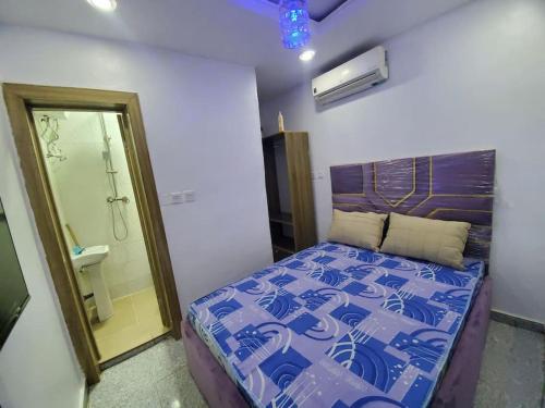 a small bedroom with a bed and a shower at DINERO JADE - One Bedroom Apartment in Lagos
