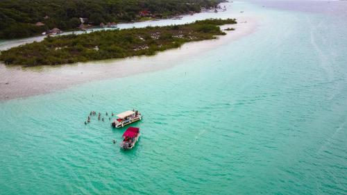 two boats in the water next to a beach at Che Bacalar Hostel & Bar Adults Only in Bacalar
