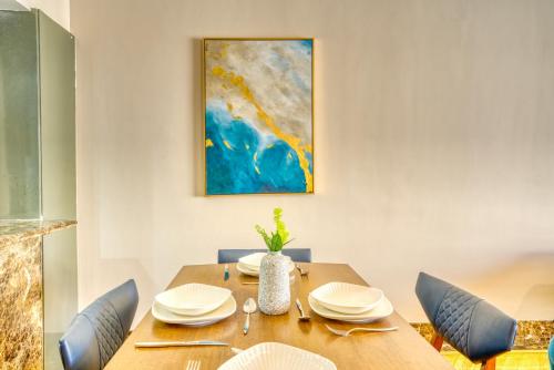 a dining room table with chairs and a painting on the wall at LOFTS by Elegant Hospitality in Cairo