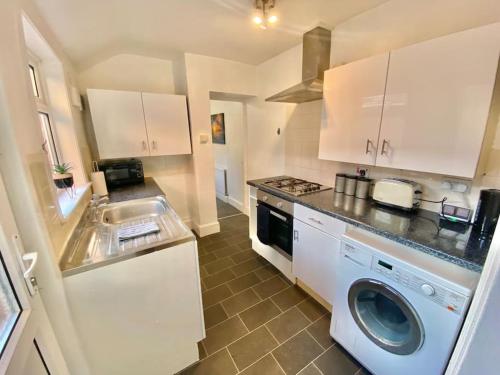 uma cozinha com uma máquina de lavar roupa e um lavatório em EasyRest House 2 Grantham - 6 Beds & Free Parking - Easy Location - Access to A1, Town Centre & Shops em Grantham