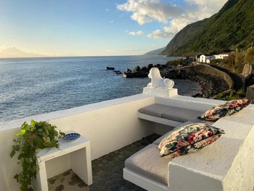 a view of the ocean with a bench and a table at Casa Tosca in Fajã de São João