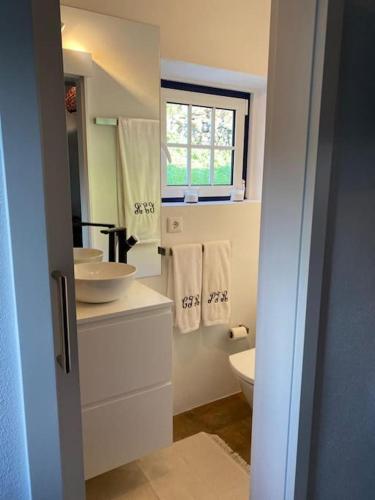 a bathroom with two sinks and a toilet and a window at Casa de São João in Fajã de São João