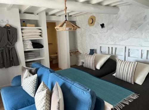 a living room with a blue couch and a bed at Casa Tosca in Fajã de São João