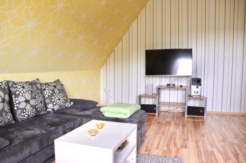 een woonkamer met een zwarte bank en een flatscreen-tv bij Ferienwohnung Paulita in Soltau