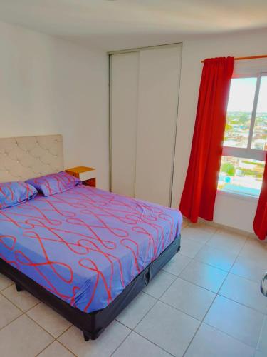 a bedroom with a bed and a window with red curtains at ALTOS DE CLERMONT in Cordoba