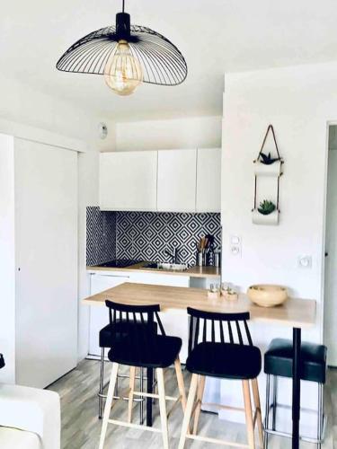 une cuisine avec une table, des chaises et une lampe dans l'établissement Cabourg T2 tout neuf Accès direct mer Grand balcon, à Cabourg