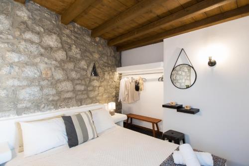 1 dormitorio con cama y pared de piedra en Mykonos Amazing Apartments 2, en Mykonos ciudad