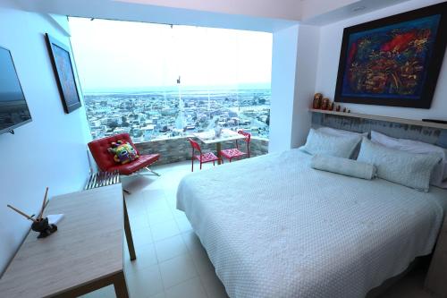 ein Schlafzimmer mit einem weißen Bett und einem großen Fenster in der Unterkunft Mejor que un Hotel in Salinas