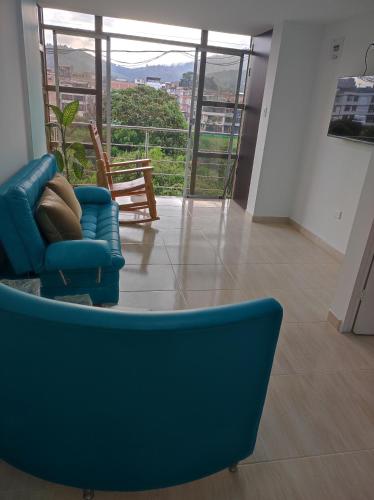 a blue couch in a living room with a large window at Apartamento portal del prado in Santa Rosa de Cabal