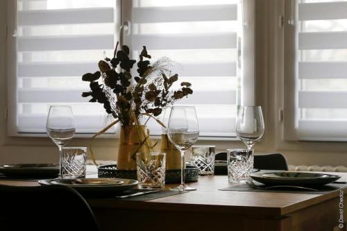 a table with wine glasses and a vase with flowers at Maison « De Ville en Vigne » in Chenôve