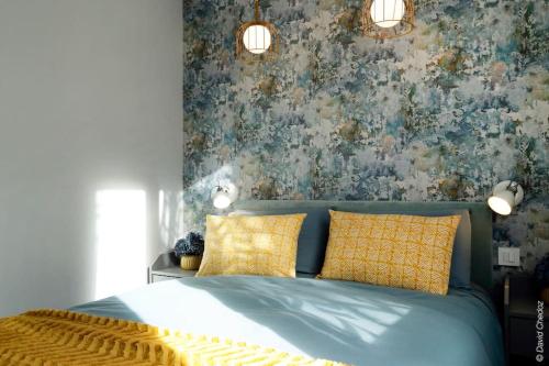 a bedroom with a blue bed with yellow pillows at Maison « De Ville en Vigne » in Chenôve