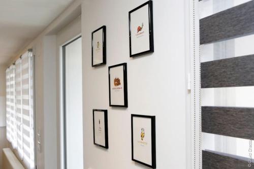 a row of framed pictures on a wall at Maison « De Ville en Vigne » in Chenôve