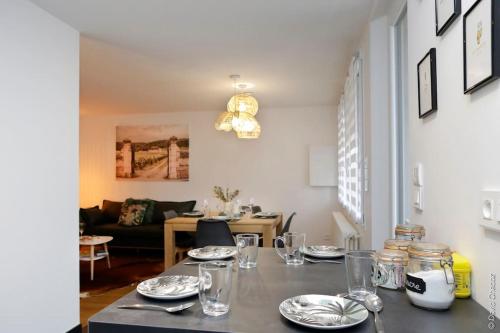 a dining room with a table with plates and glasses at Maison « De Ville en Vigne » in Chenôve