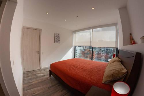 1 dormitorio con cama roja y ventana grande en Suite Downtown Quito - República del Salvador, en Quito