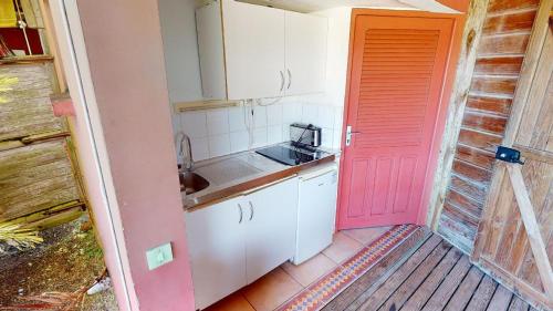 a kitchen with a red door next to a porch at Baobab Guadeloupe in Sainte-Anne