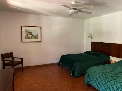 a bedroom with two beds and a ceiling fan at Hotel Posada Santa Rita in Mascota