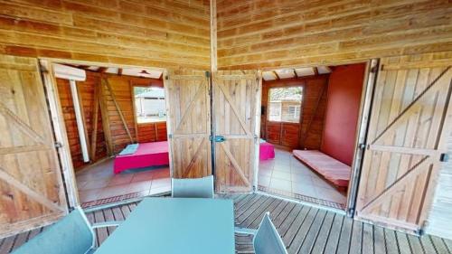 Habitación con puertas y bancos en una cabaña de madera. en Baobab Guadeloupe, en Sainte-Anne