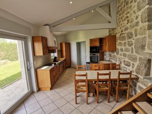 cocina con mesa, sillas y pared de piedra en Gite du platane, en Grazac