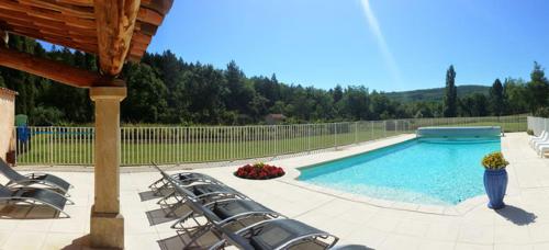 a swimming pool with lounge chairs next to a fence at Gîte Le Sirocco Le Moulin de Prédelles in Reillanne