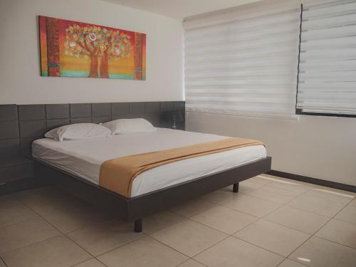1 cama en un dormitorio con una pintura en la pared en #2 Suite luxury - Puerto Santa Ana, en Guayaquil