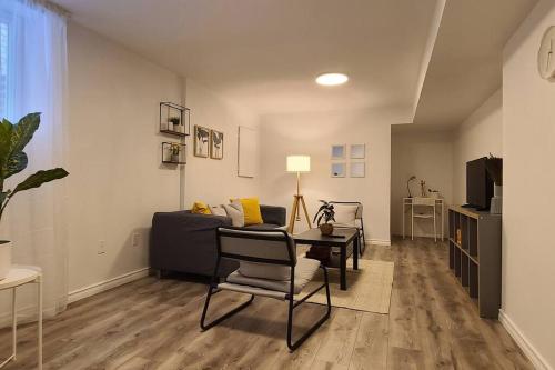 uma sala de estar com um sofá, uma mesa e cadeiras em Cozy 2-bedroom lower unit! em Barrie