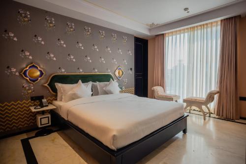 ein Schlafzimmer mit einem großen Bett und einem großen Fenster in der Unterkunft Bur'Dera - a Boutique Luxury Hotel in Jaipur