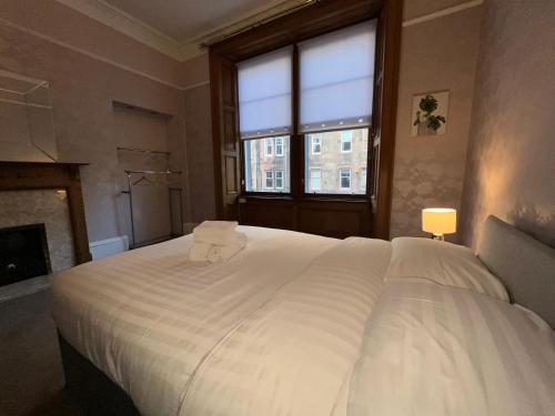 a bedroom with a large white bed with a fireplace at Bright 3 Bedroom Edinburgh City Apt in Edinburgh