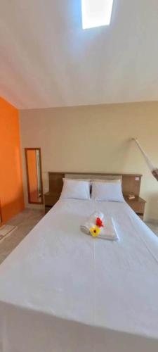 a white bed with a rubber duck on top of it at Suites Canoa in Aracati