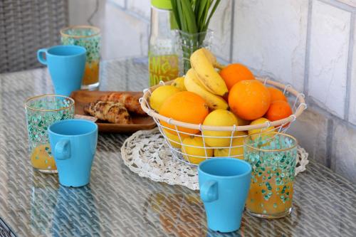 a basket of fruit on a table with blue cups at Apartment Lana in Dubrovnik