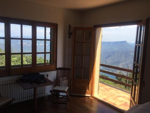 a room with two large windows and a wooden table at Casa de muntanya Can Coll de Susqueda Girona in Susqueda