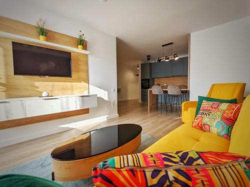 a living room with a yellow couch and a table at Cluj Airport Apartment in Cluj-Napoca