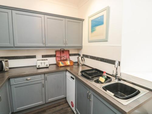 a kitchen with gray cabinets and a sink at The Link in Torquay