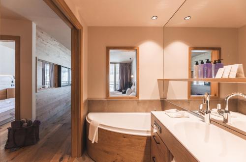 a bathroom with a tub and a sink and mirror at Familienhotel Familiamus in Maranza