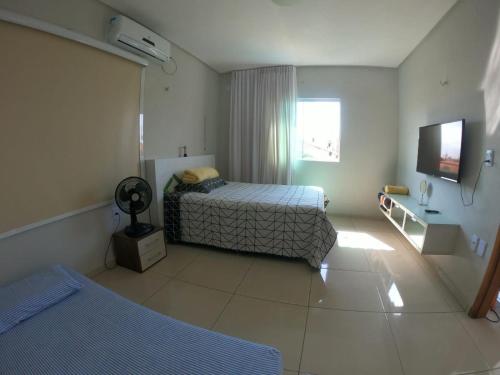 ein Hotelzimmer mit 2 Betten und einem TV in der Unterkunft Casa para Família com Piscina in Luis Correia
