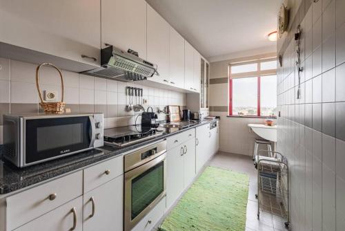 a kitchen with white cabinets and a green rug at Sunset Apartment Vila Nova de Gaia in Vila Nova de Gaia