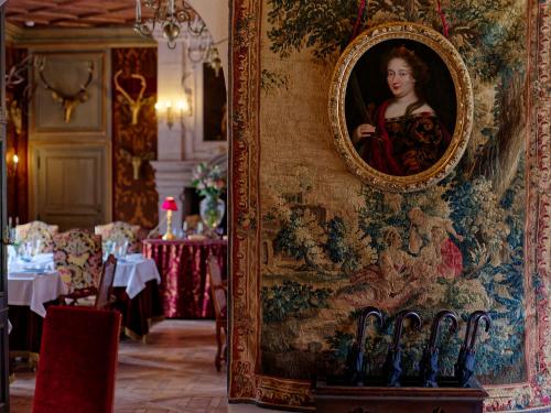 a painting of a woman on a wall in a restaurant at Relais & Château Louise de La Vallière in Reugny
