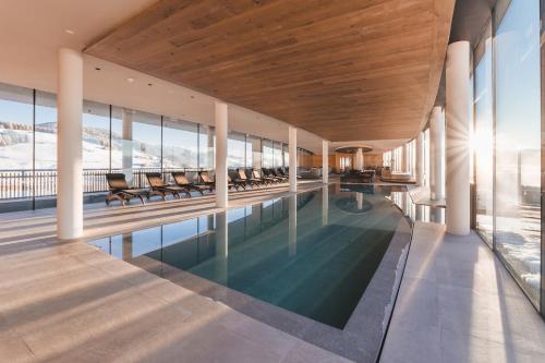 an indoor swimming pool with chairs in a building at Familienhotel Familiamus in Maranza