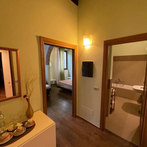 a bathroom with a mirror and a room with a bed at Guest-House Del Corso in Montepulciano