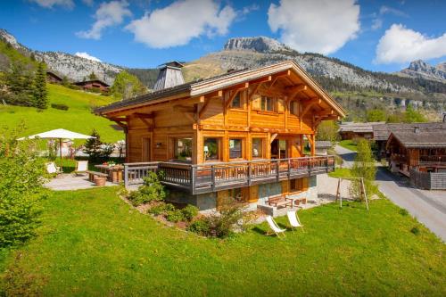 a log home with a large deck and mountains at Chalet Le Charmieux - OVO Network in Le Grand-Bornand