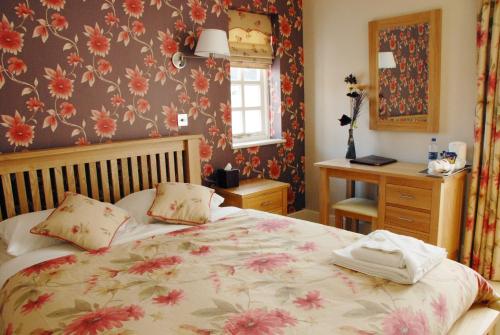 een slaapkamer met een bed met bloemenbehang bij The Carlton in Rugby