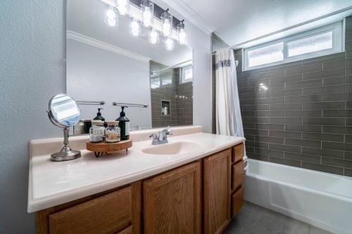 a bathroom with a sink and a mirror and a tub at Private Pool Oasis/Disney 15mins /Disney+ HBO/Gym in Placentia