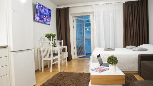 a small white room with a bed and a table at Heart of Oulu, studio with parking in Oulu