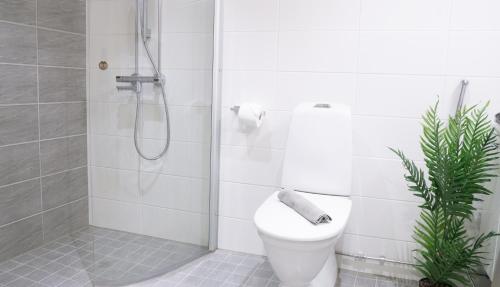 a white bathroom with a shower and a toilet at Heart of Oulu, studio with parking in Oulu