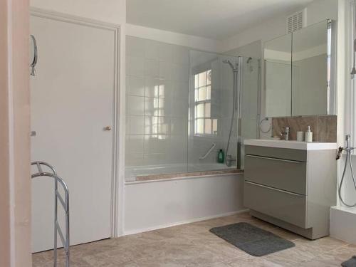 bagno bianco con doccia e lavandino di A stunning 3 bedroom house a Londra