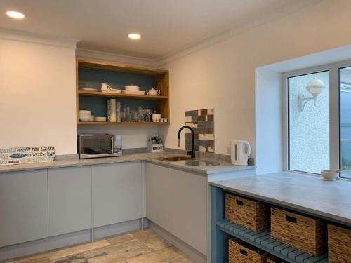 a kitchen with white cabinets and a sink and a window at Treloyhan Lodge in St Ives