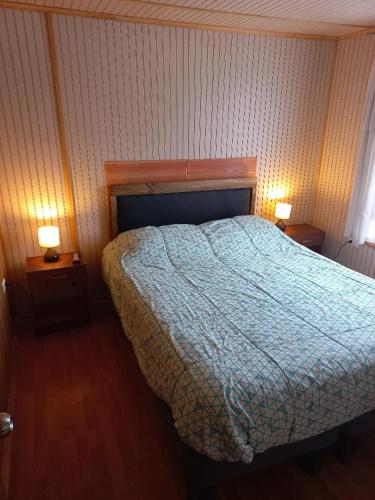 a bedroom with a bed and two night stands with lamps at Cabaña Horcon in Puchuncaví