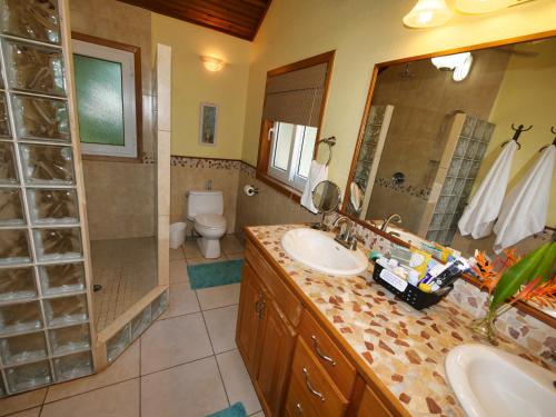 a bathroom with two sinks and a shower and a toilet at Casa Buena Vida in West Bay