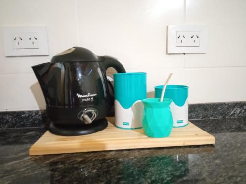 Arana的住宿－Espacio LORENZO，咖啡壶和切纸板上的两个杯子