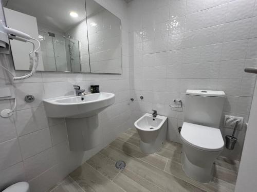 a white bathroom with a toilet and a sink at Hotel Búzio in Sines